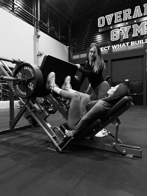 Danni treinando aluna no leg press na Overall Gym